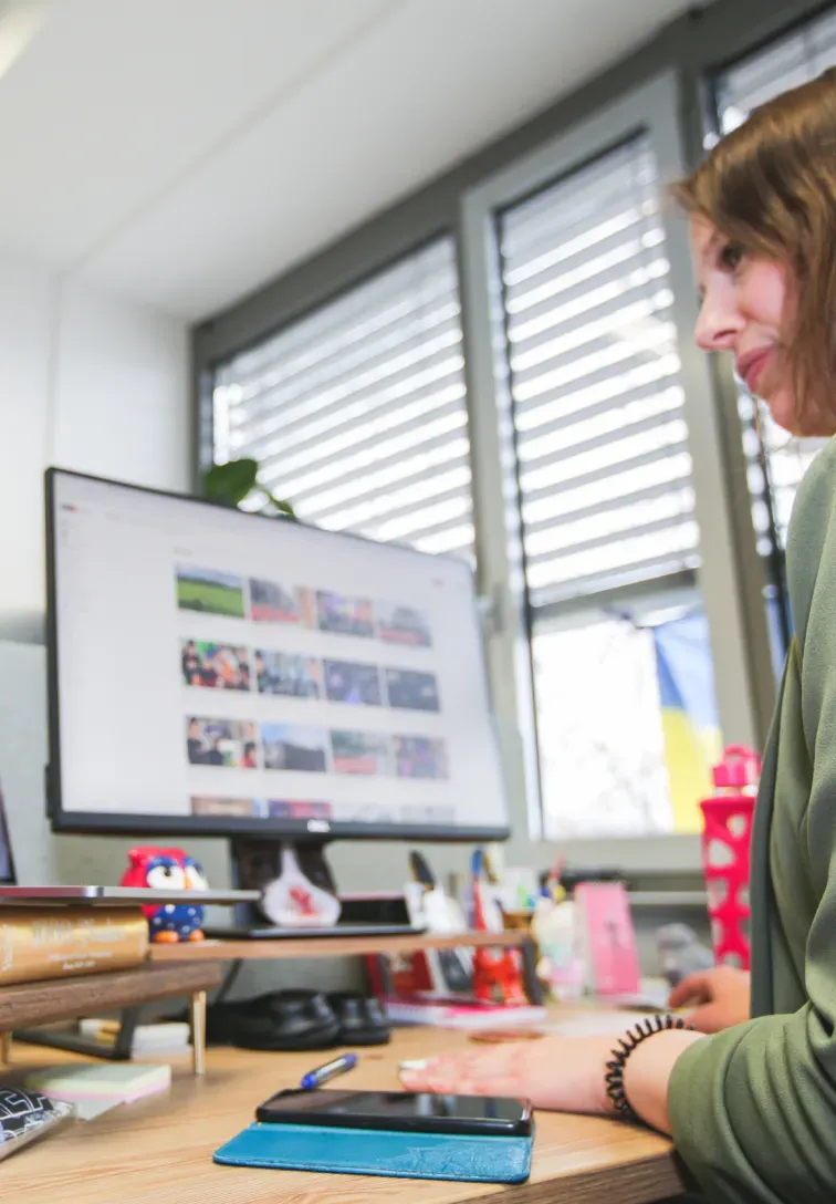 A woman glancing over an office desk with a monitor