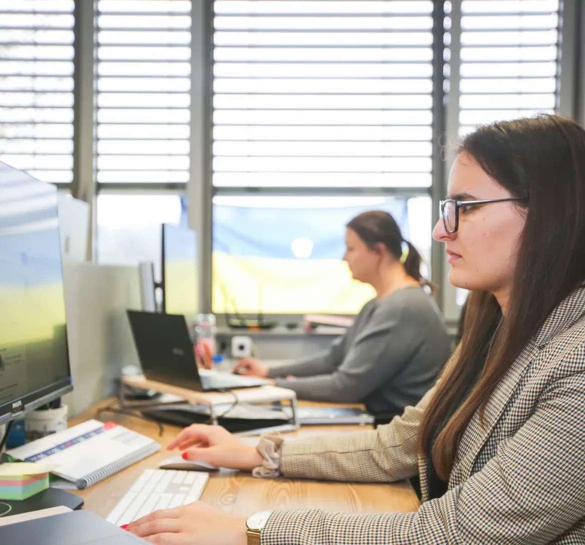 Two women sitting at an office desk, up close in profile